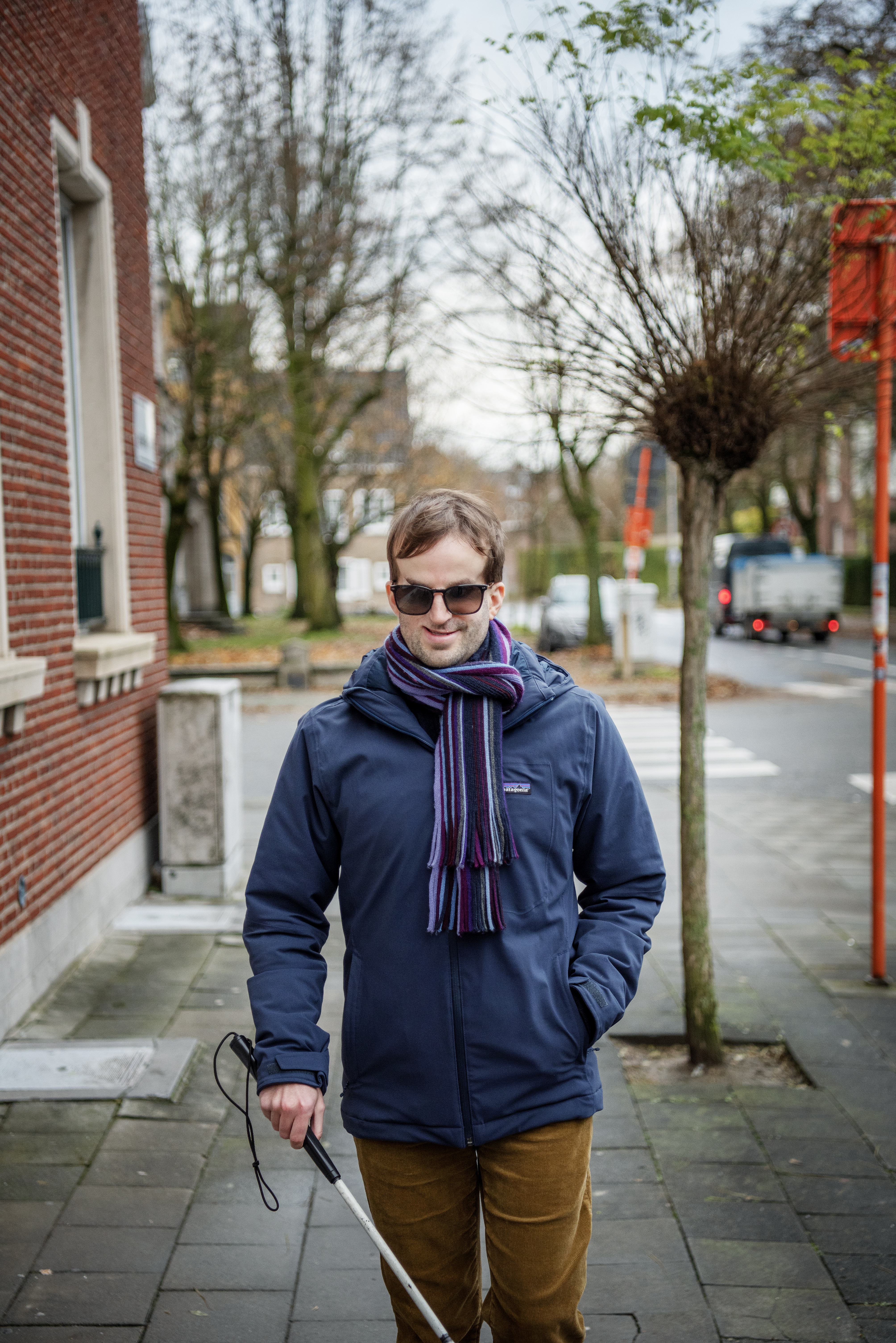 Piet Devos buiten met zijn bril op en geleidenstok