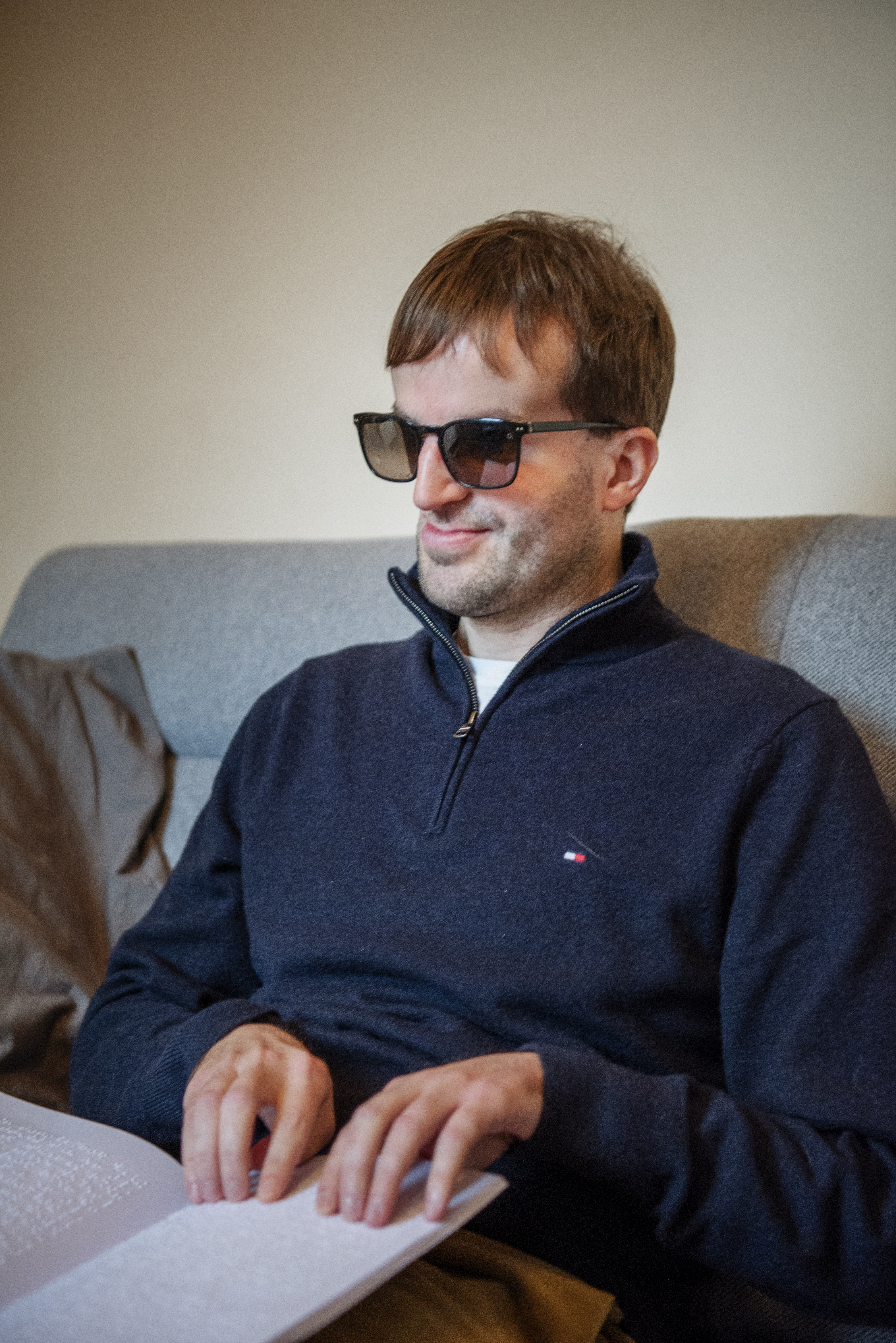 Piet Devos leest uit zijn brailleboek in de zetel